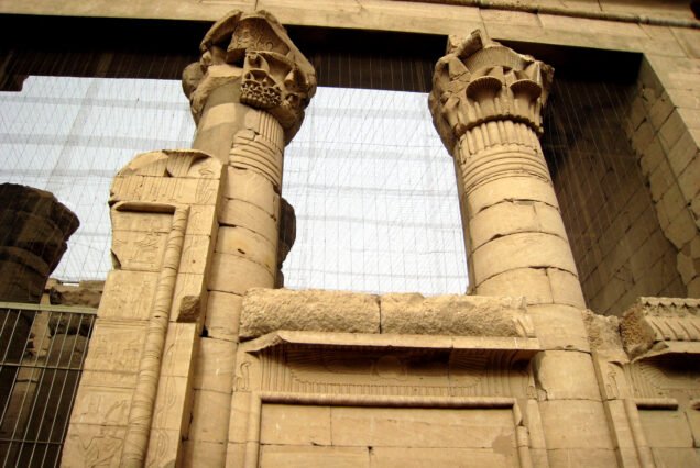 Le colonne con capitelli floreali del tempio di Kalabsha viste dal basso, con la rete di protezione moderna sopra il colonnato