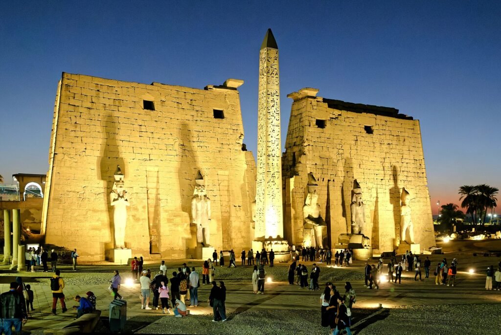 Il Tempio di Luxor illuminato dopo il tramonto, con i visitatori davanti al pilone