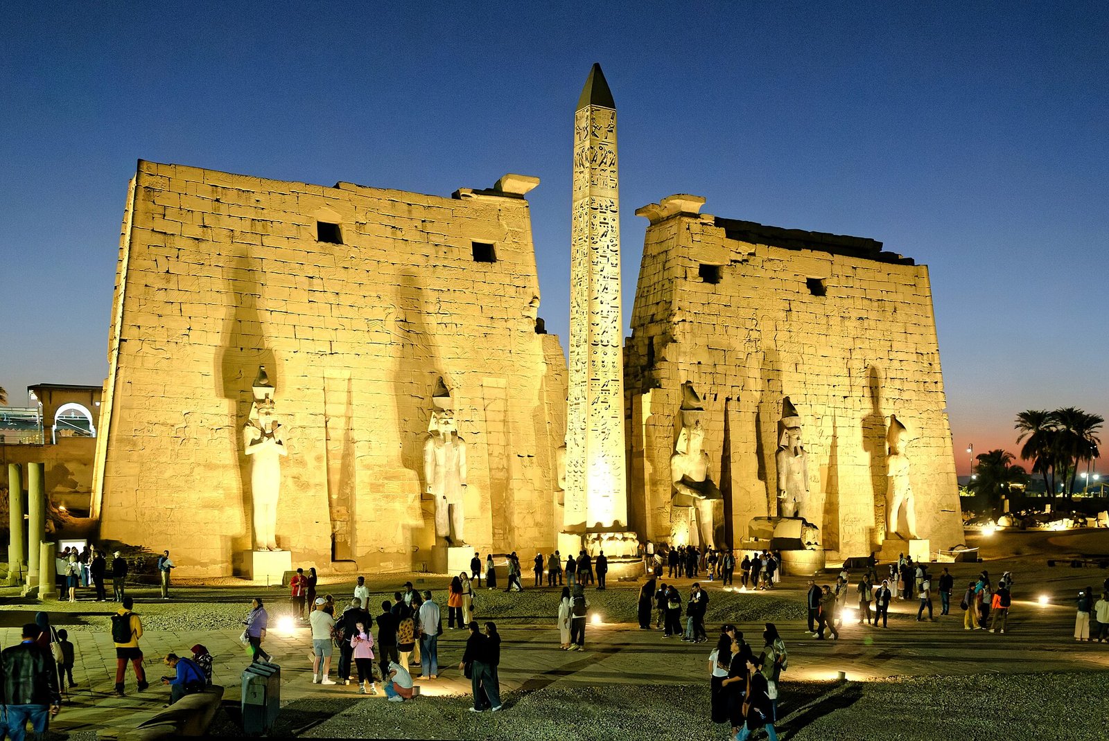 Il Tempio di Luxor illuminato dopo il tramonto, con i visitatori davanti al pilone