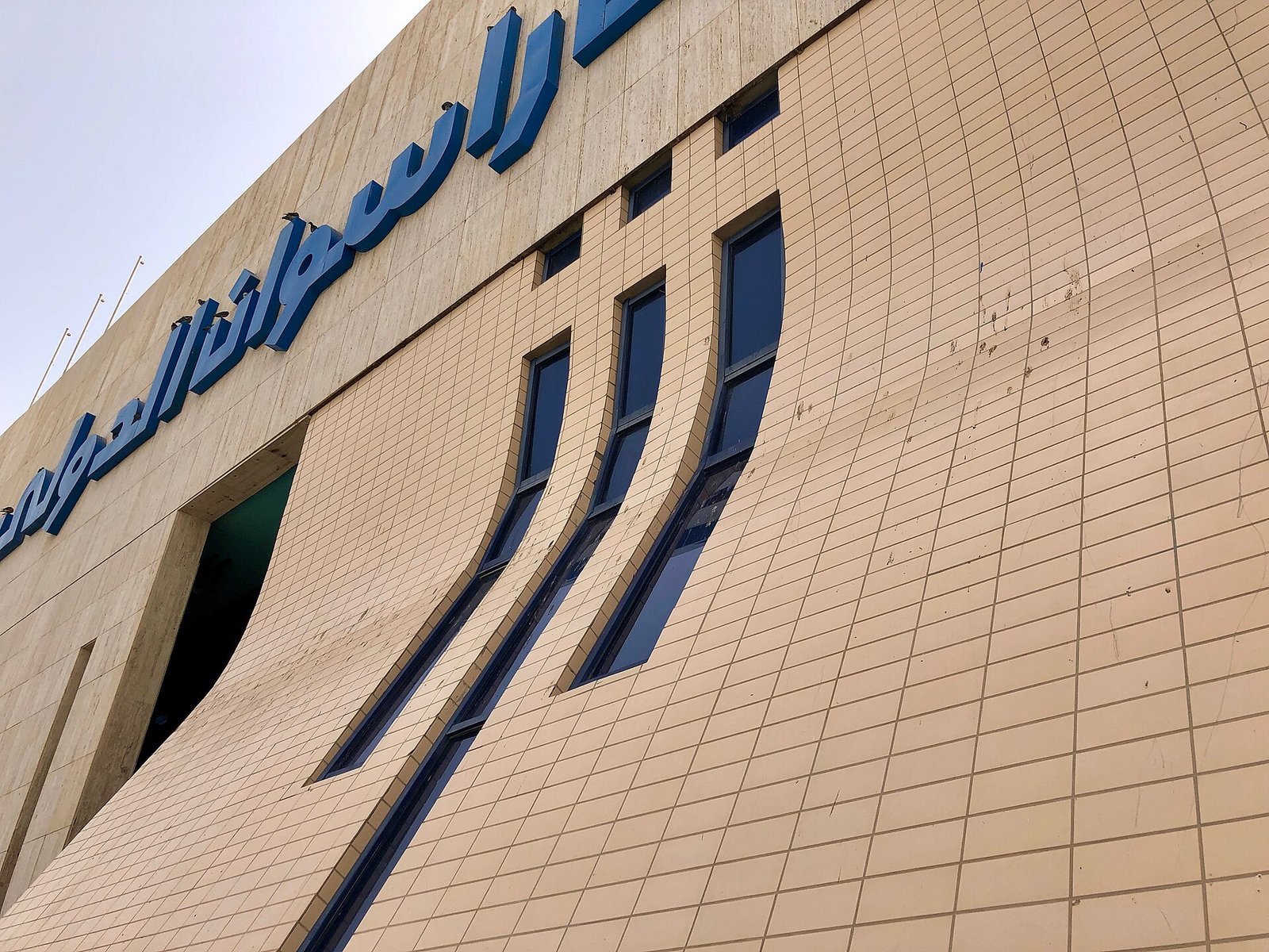 La facciata in pietra chiara del terminal dell'aeroporto di Assuan con la scritta in arabo