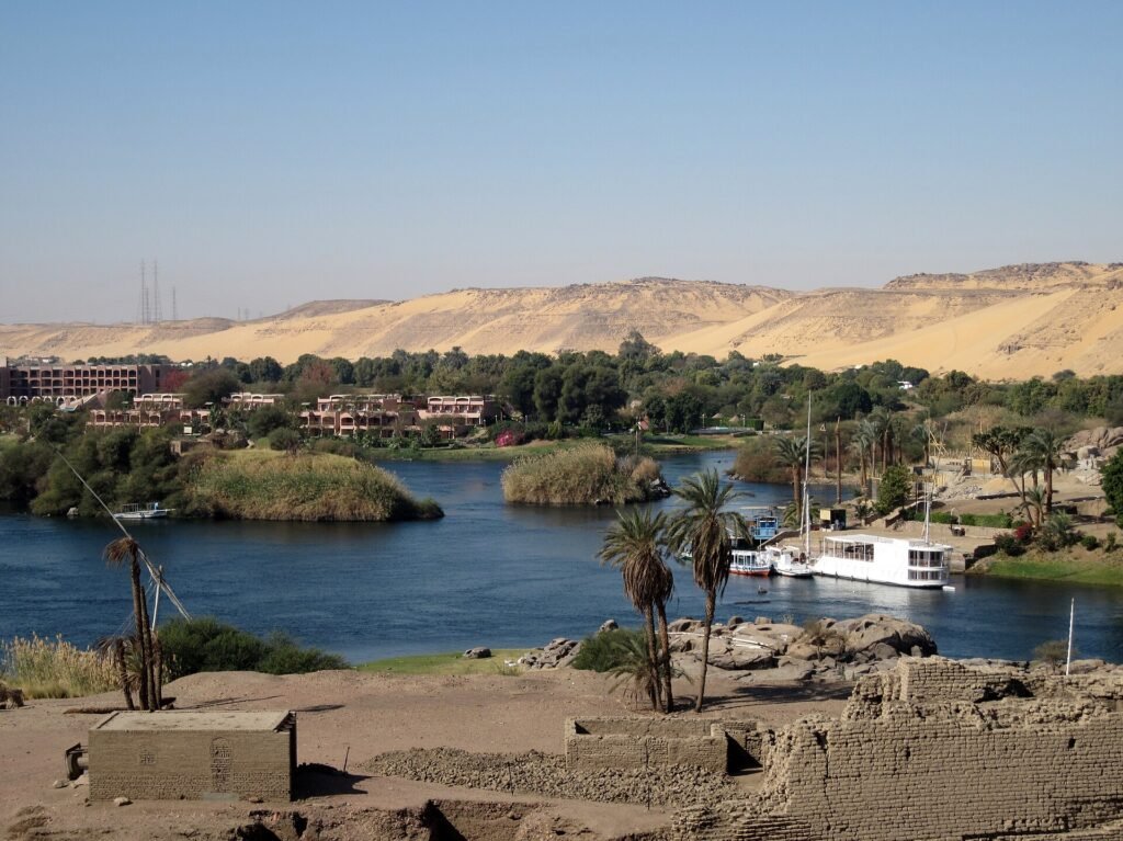 Il Nilo ad Assuan visto dall'isola di Elefantina, con le rovine in primo piano e le dune della riva occidentale sullo sfondo