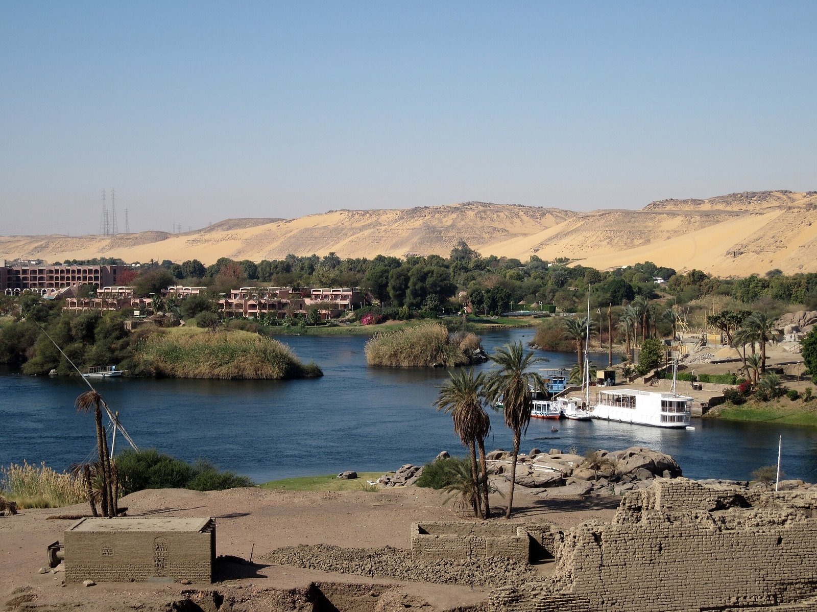 Il Nilo ad Assuan visto dall'isola di Elefantina, con le rovine in primo piano e le dune della riva occidentale sullo sfondo