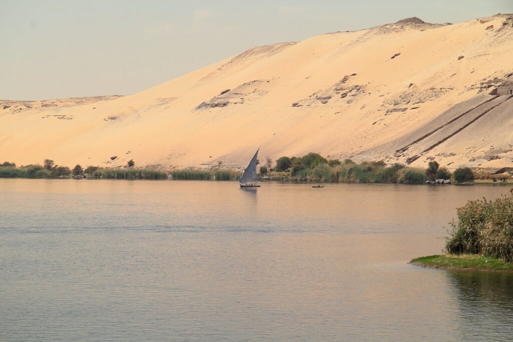 Una feluca solitaria sul Nilo davanti alle dune dorate di Assuan
