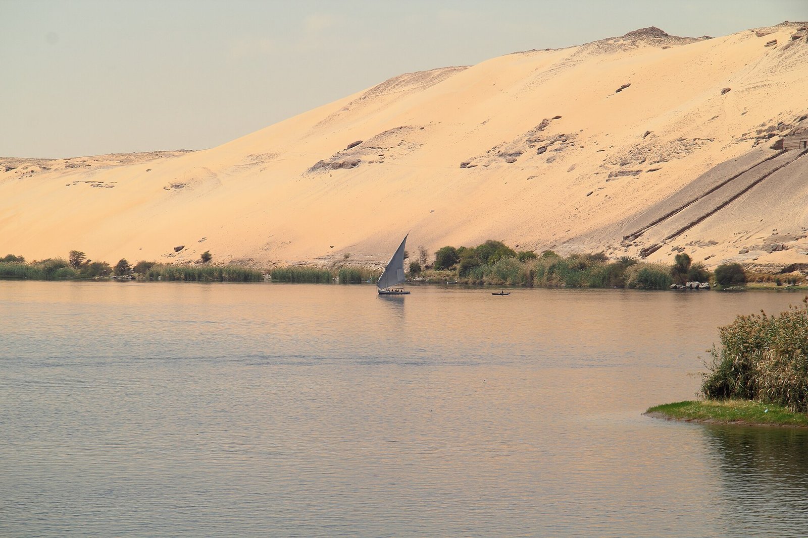 Una feluca solitaria sul Nilo davanti alle dune dorate di Assuan