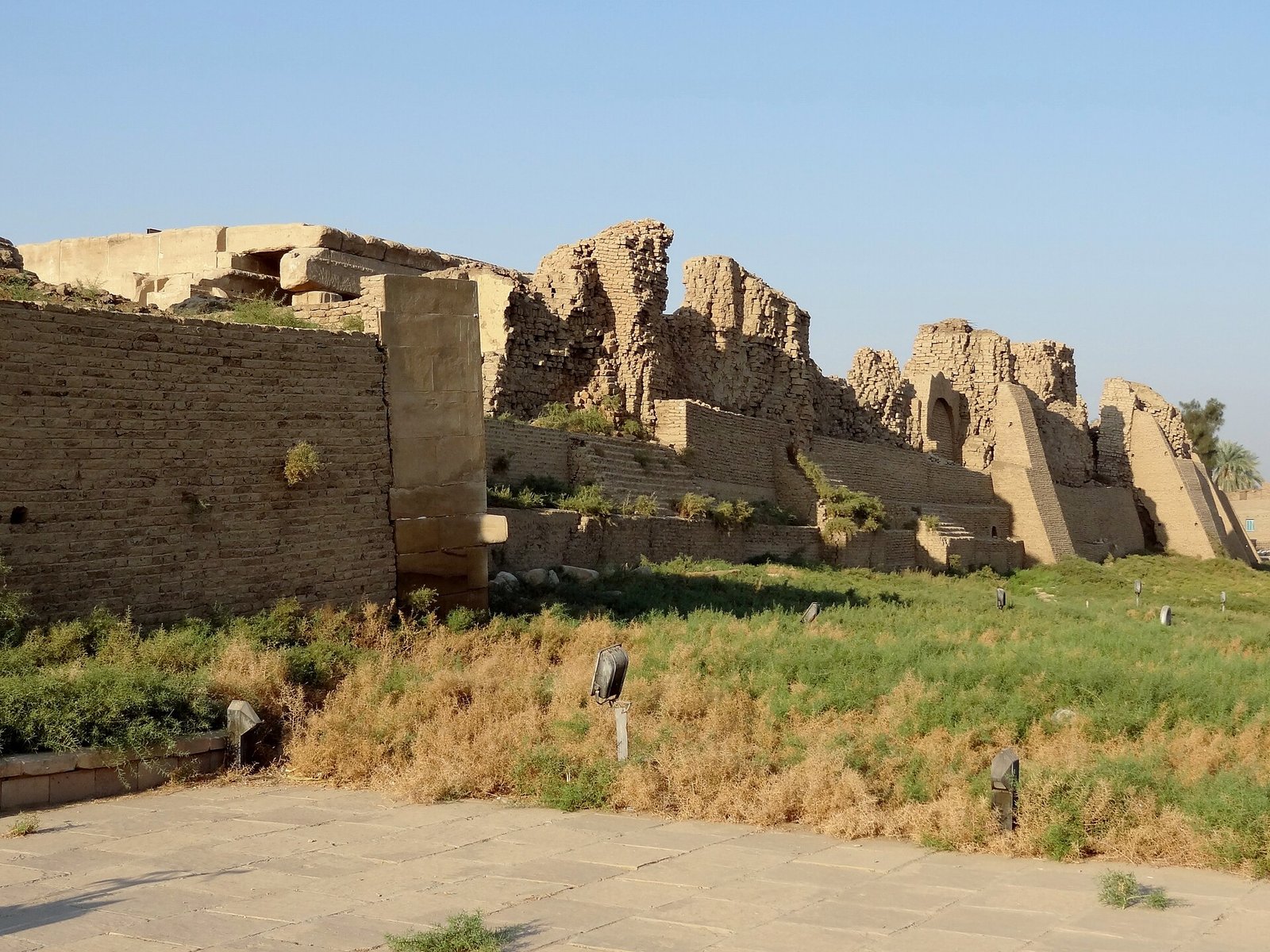 Il muro di cinta in mattoni crudi del complesso di Dendera, in rovina, con la vegetazione bassa in primo piano