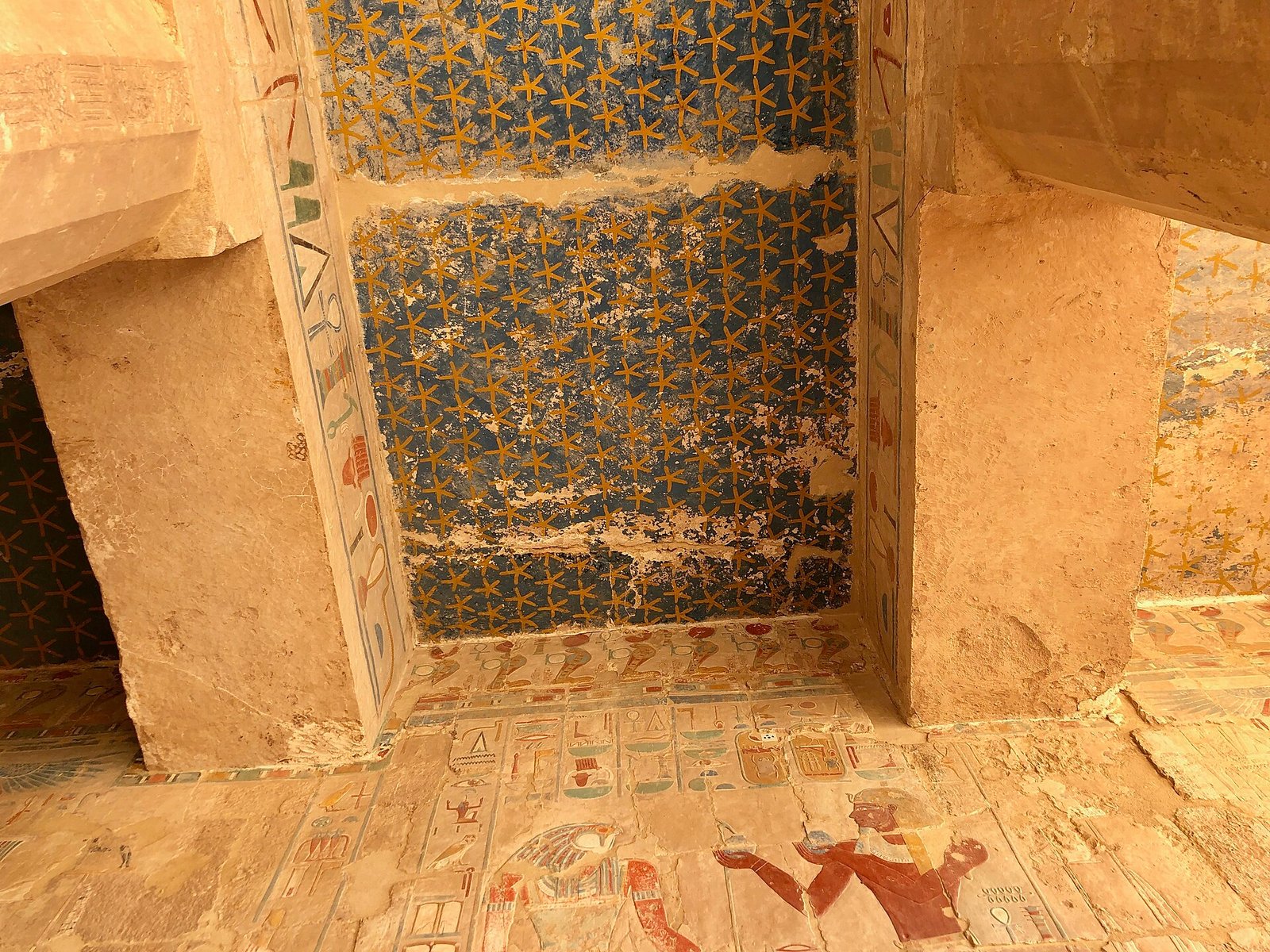 Il soffitto blu dipinto con stelle dorate in una sala interna del tempio di Hatshepsut, con l'architrave geroglifico ancora colorato