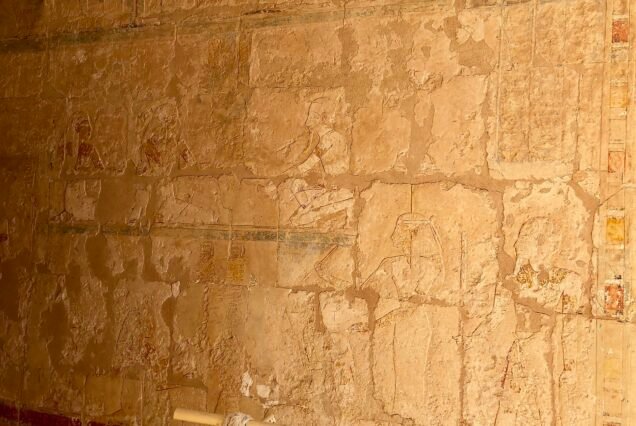 Una parete in rilievo molto erosa all'interno del tempio di Hatshepsut, con tracce di colore lungo le fasce decorative
