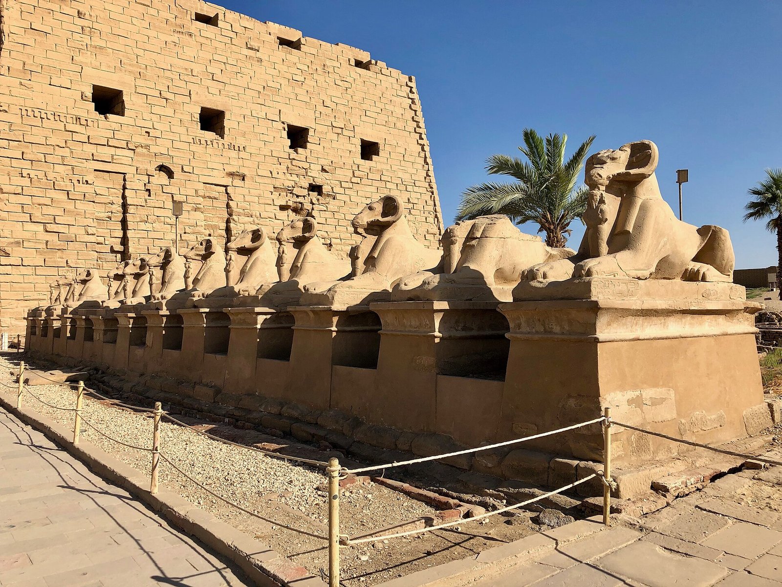Il viale delle sfingi con testa di ariete allineate davanti al primo pilone di Karnak, sotto il cielo azzurro