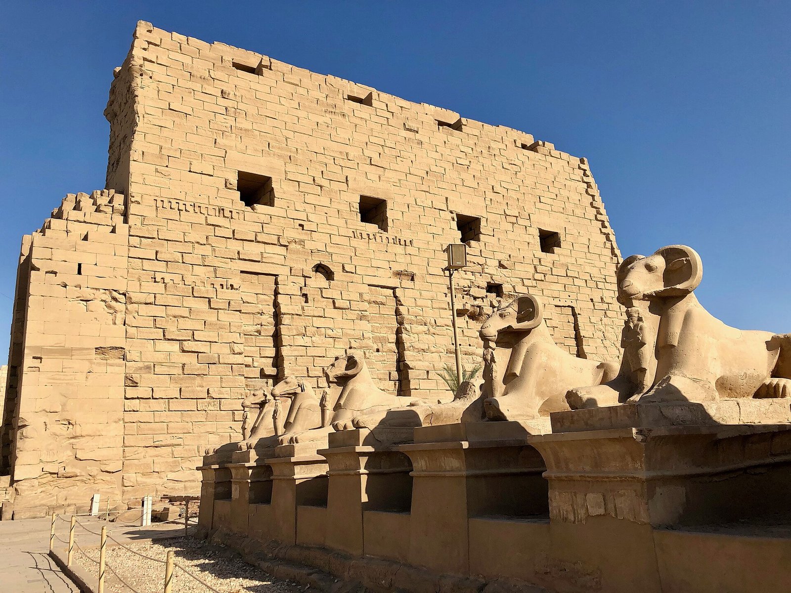Il primo pilone di Karnak, imponente e incompiuto, con le sfingi con testa di ariete allineate ai suoi piedi
