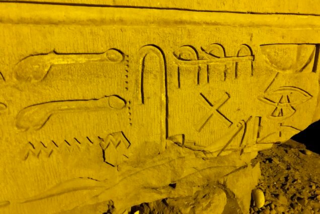 Dettaglio ravvicinato di geroglifici incisi su un blocco caduto a Kom Ombo, illuminato di notte