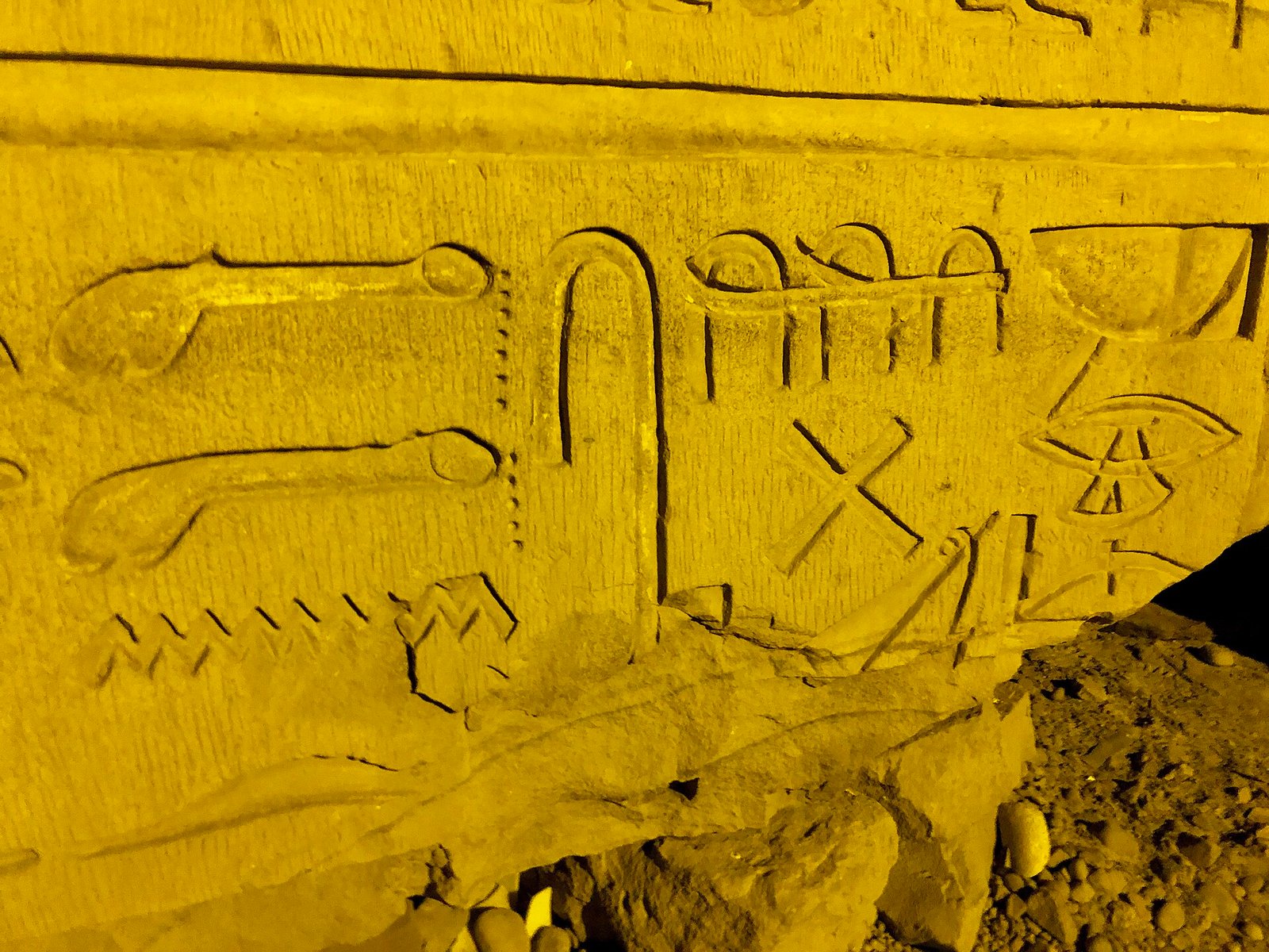 Dettaglio ravvicinato di geroglifici incisi su un blocco caduto a Kom Ombo, illuminato di notte