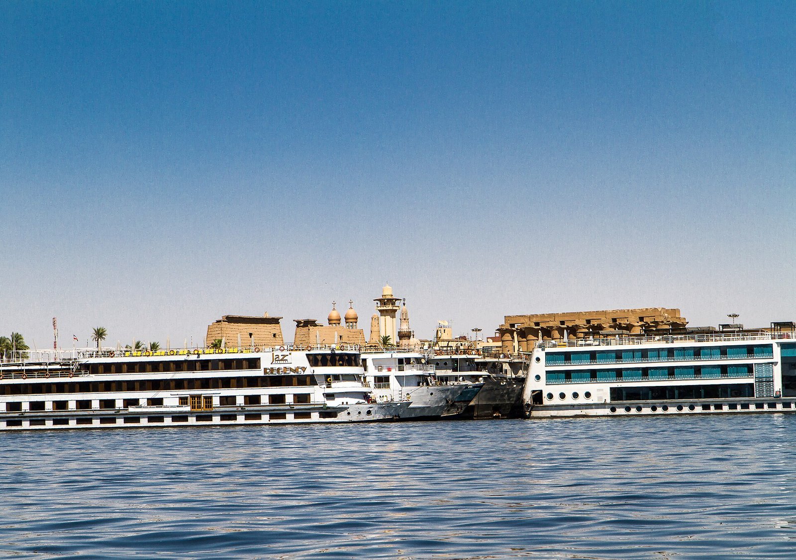 Le navi da crociera ormeggiate davanti al tempio di Luxor, che si intravede sulla riva alle loro spalle