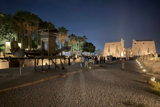 Il viale delle sfingi di notte verso il tempio di Luxor illuminato, con la riproduzione moderna di una barca sacra esposta in primo piano