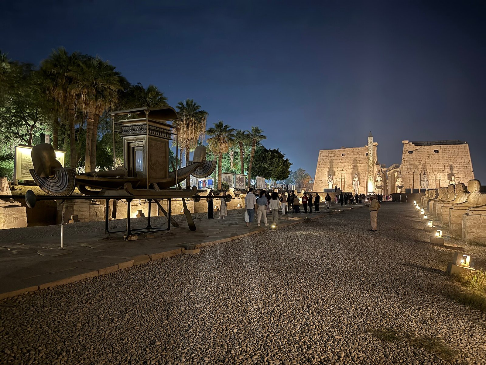 Il viale delle sfingi di notte verso il tempio di Luxor illuminato, con la riproduzione moderna di una barca sacra esposta in primo piano
