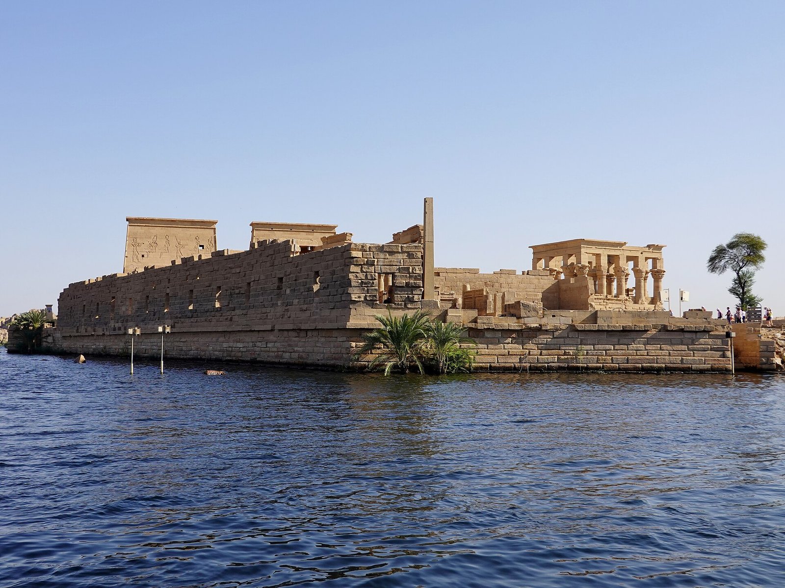 L'isola di Philae vista dall'acqua, con il muro di cinta, i piloni del tempio e il chiosco colonnato sulla destra