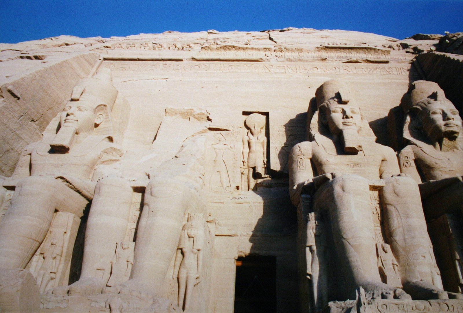 I colossi seduti della facciata del Grande Tempio di Abu Simbel visti dal basso, con le figure minori fra le gambe