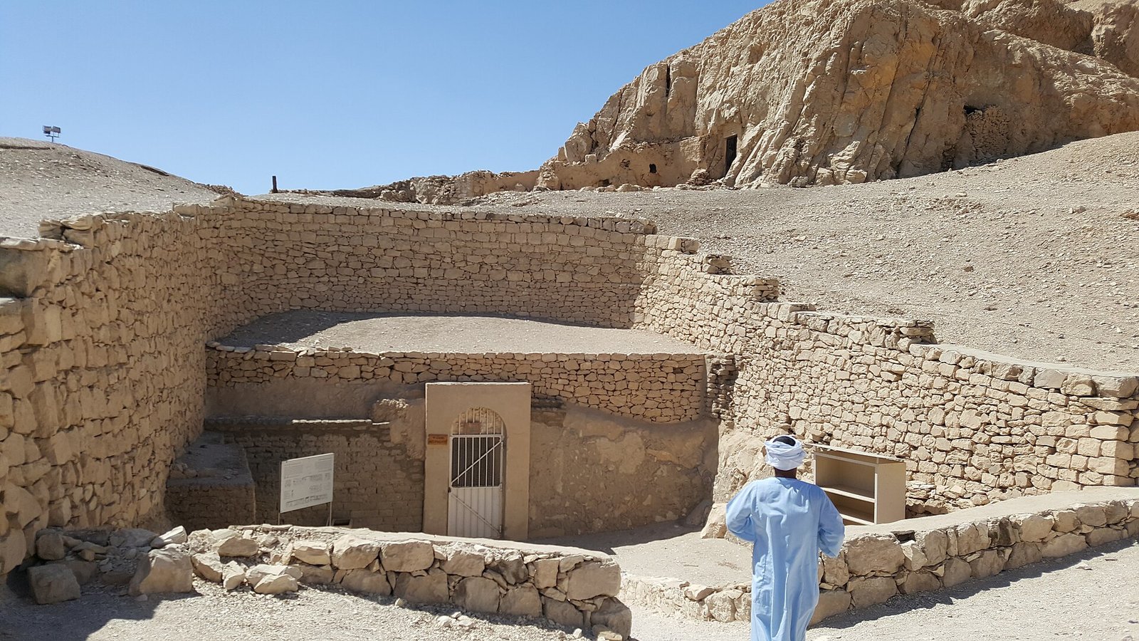 L'ingresso recintato di una tomba dei nobili a Luxor ovest, con il cancello metallico e la collina di roccia alle spalle