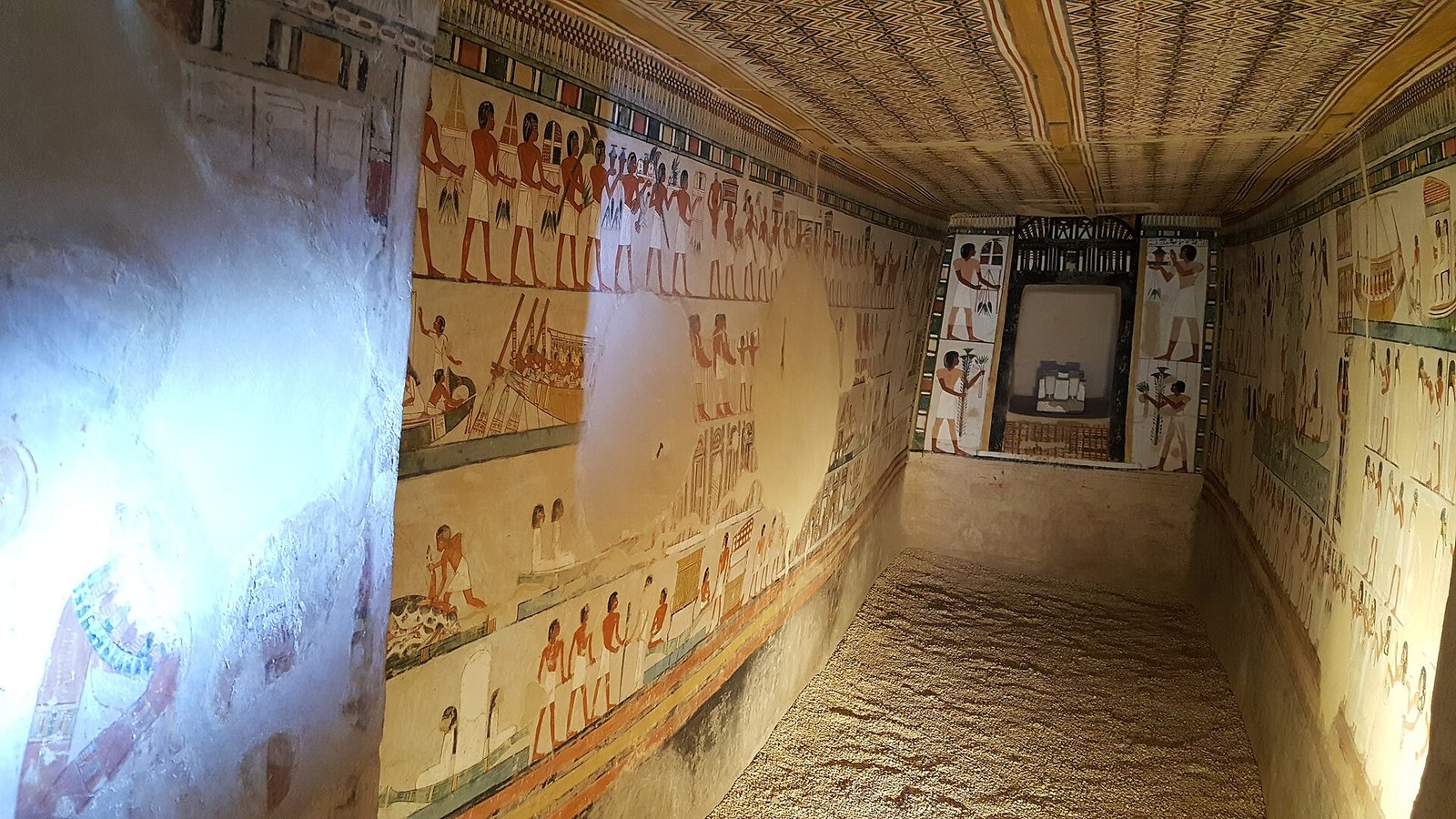 Una camera dipinta in una tomba dei nobili a Luxor, con le pareti coperte di registri di portatori di offerte e barche e il soffitto decorato
