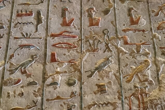 Geroglifici scolpiti a rilievo con tracce del colore originale su una parete di tomba nella Valle dei Re, con la superficie in parte consumata