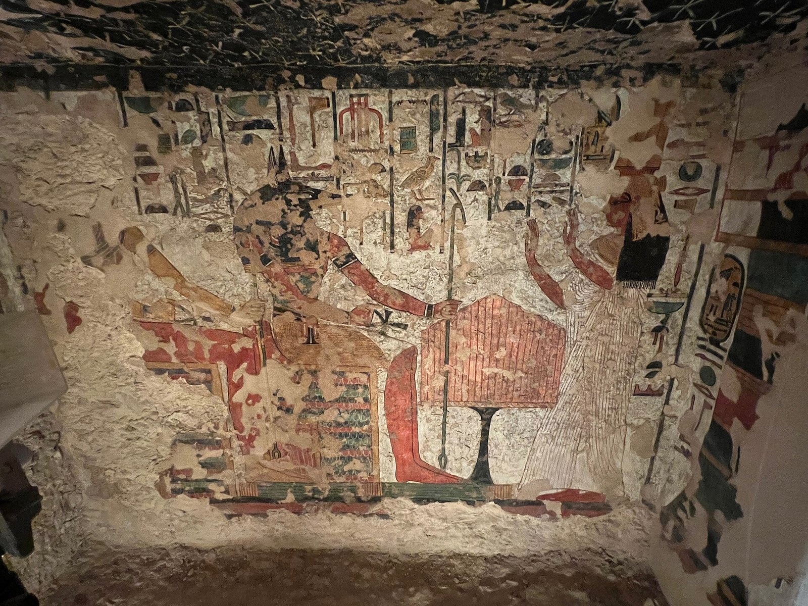 Una parete dipinta molto rovinata in una tomba della Valle delle Regine, con il soffitto stellato e ampie perdite di intonaco