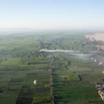La riva ovest di Luxor vista dall'alto all'alba, con i campi verdi a scacchiera, alcune mongolfiere in volo e la linea netta dove la coltivazione finisce e comincia il deserto
