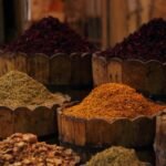Tini di legno colmi di spezie in un mercato egiziano, con ibisco essiccato, fiori di cartamo e erbe aromatiche nella luce calda