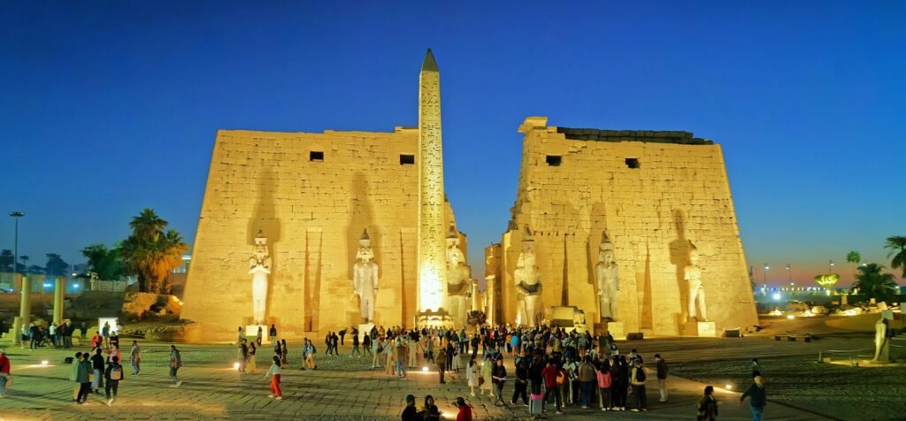 Il pilone del tempio di Luxor illuminato all'ora blu, con l'obelisco e i colossi in luce calda contro il cielo scuro