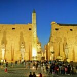 Il pilone del tempio di Luxor illuminato all'ora blu, con l'obelisco e i colossi in luce calda contro il cielo scuro