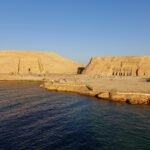 I due templi di Abu Simbel visti dal lago Nasser nella luce calda del tardo pomeriggio, con le colline artificiali che li racchiudono