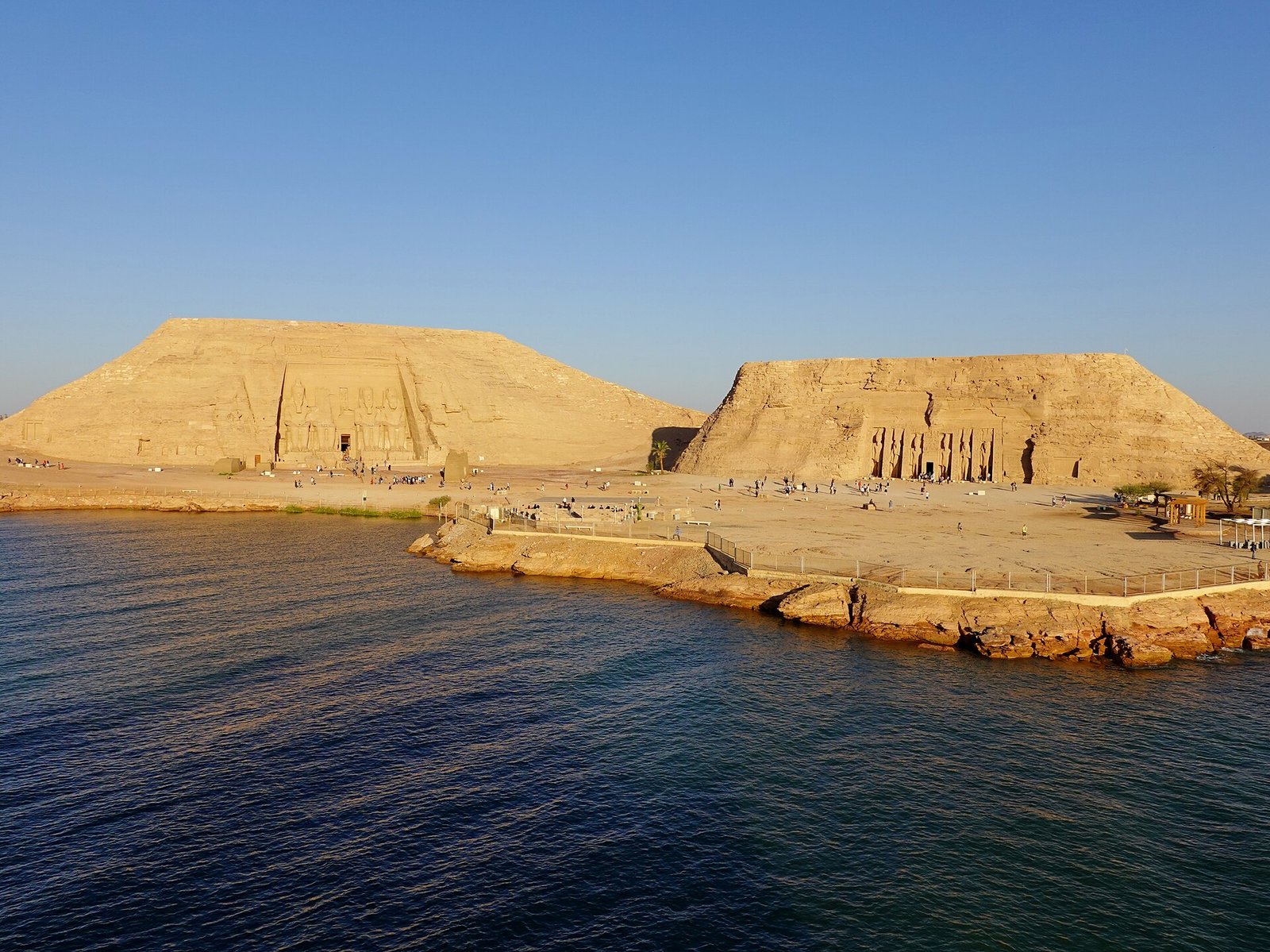 I due templi di Abu Simbel visti dal lago Nasser nella luce calda del tardo pomeriggio, con le colline artificiali che li racchiudono