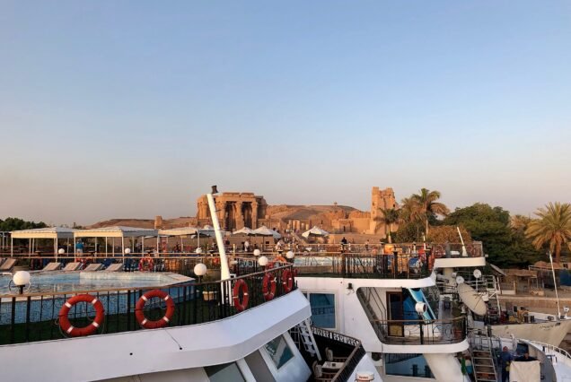 Le navi da crociera ormeggiate sul Nilo al tramonto, con il tempio di Kom Ombo illuminato sulla riva alle loro spalle