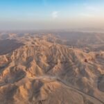 Veduta aerea al sole basso delle colline desertiche della riva ovest di Luxor, con i valloni che nascondono le tombe reali