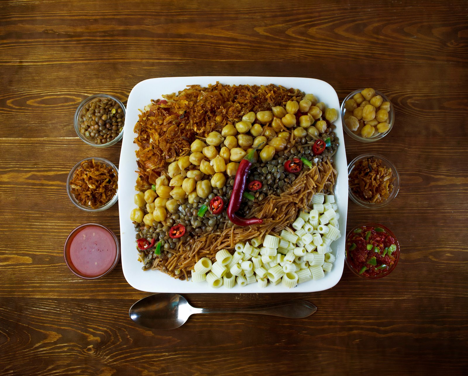 Piatto di koshari con lenticchie, ceci, cipolla fritta e salsa di pomodoro