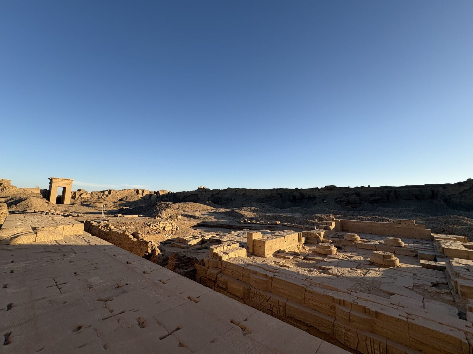 Veduta del recinto di Dendera al tramonto con mura in mattoni crudi e blocchi antichi