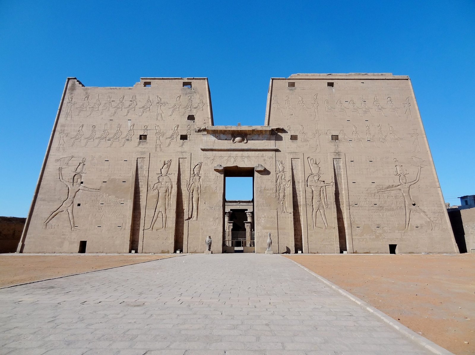 Il pilone del tempio di Horus a Edfu visto di fronte, con la strada lastricata e i falchi in pietra