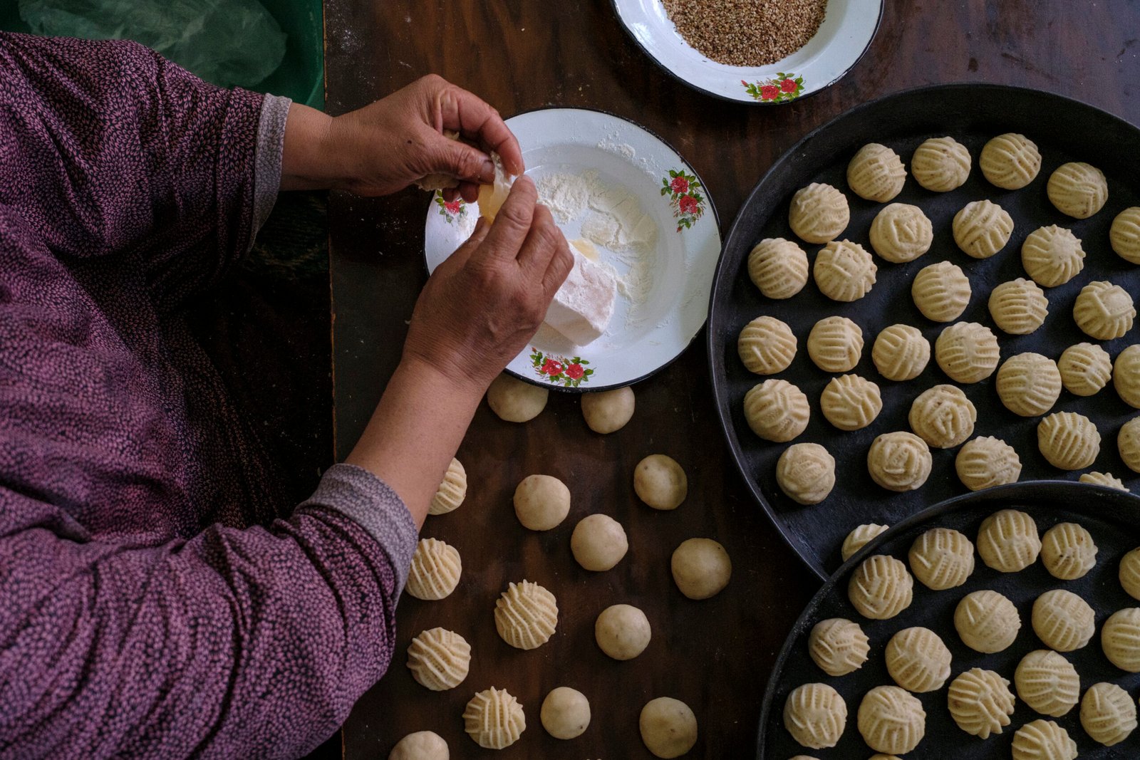 Mani che modellano i kahk della festa e vassoi di dolci già formati