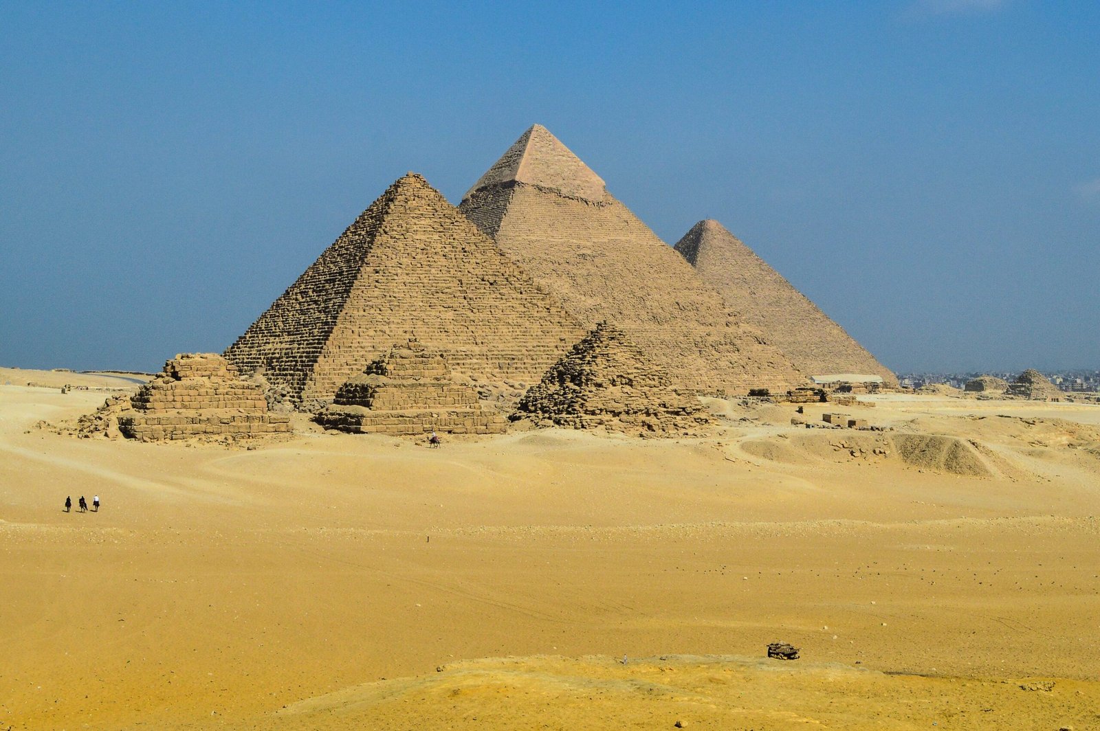 Le tre piramidi di Giza allineate viste da sud ovest sopra la sabbia dorata del pianoro.