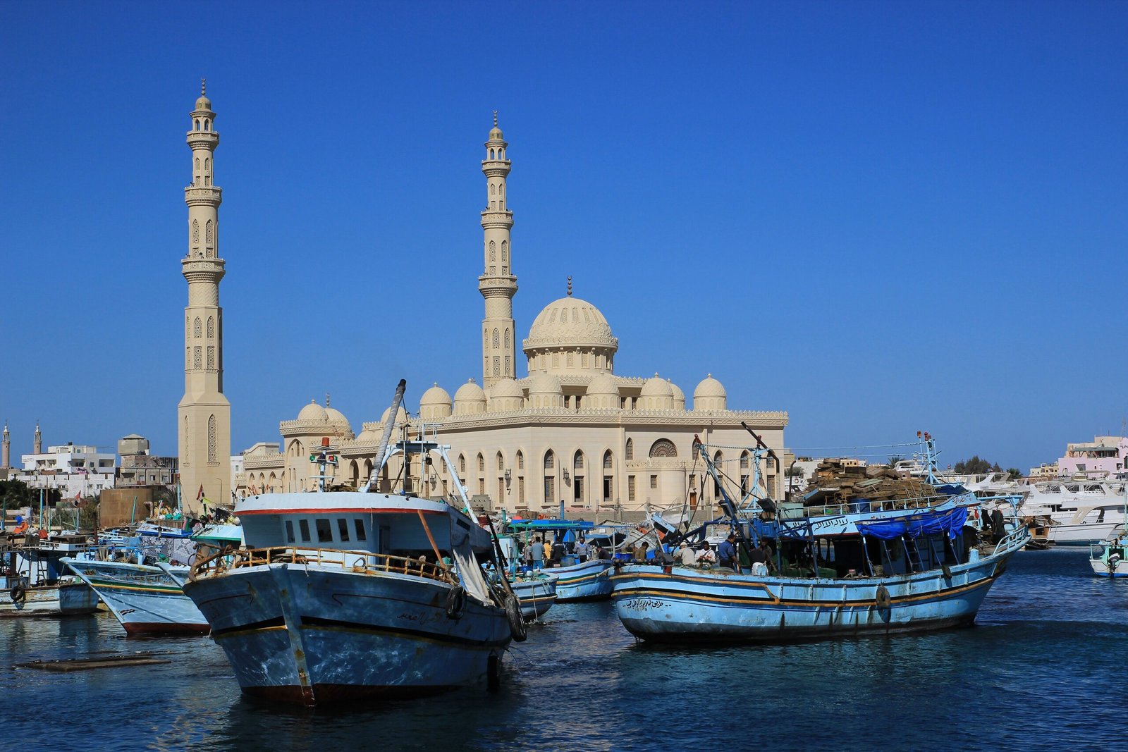 Grande moschea del porto di Hurghada con due minareti e cupola chiara, davanti pescherecci di legno azzurro ormeggiati