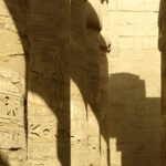 Luce radente sulle colonne della sala ipostila di Karnak con rilievi e geroglifici incisi