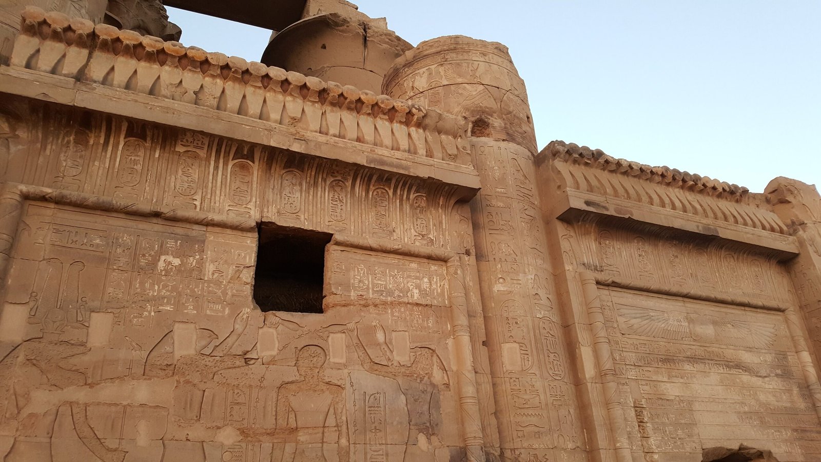 Muro del tempio di Kom Ombo con cornice scolpita e colonna nella luce calda della sera