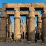 Colonne e statue reali nel cortile del Tempio di Luxor sotto una luce calda e radente