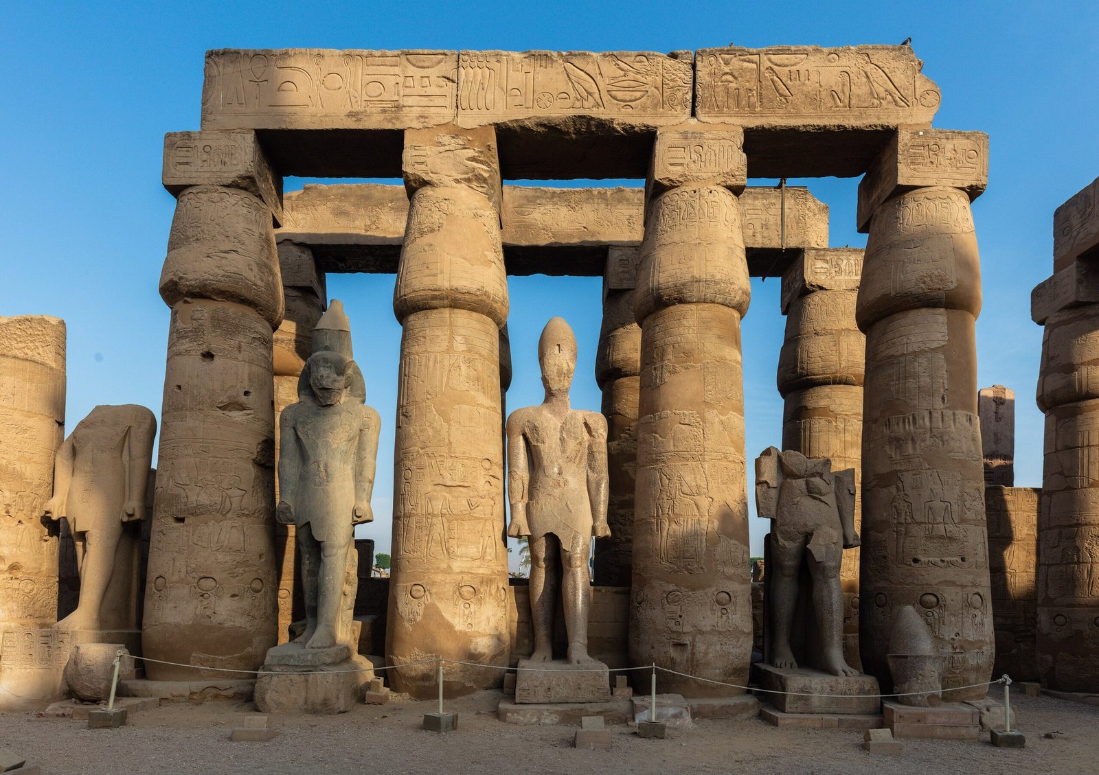 Colonne e statue reali nel cortile del Tempio di Luxor sotto una luce calda e radente