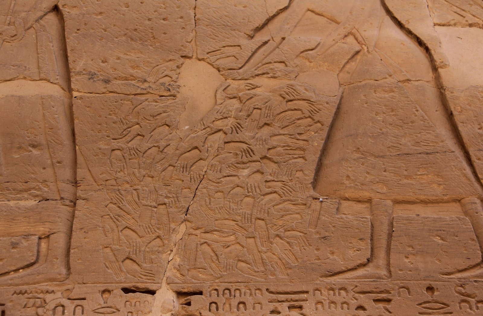 Rilievo egizio scolpito nella parete esterna di Medinet Habu, con figure e file di mani incise nell'arenaria