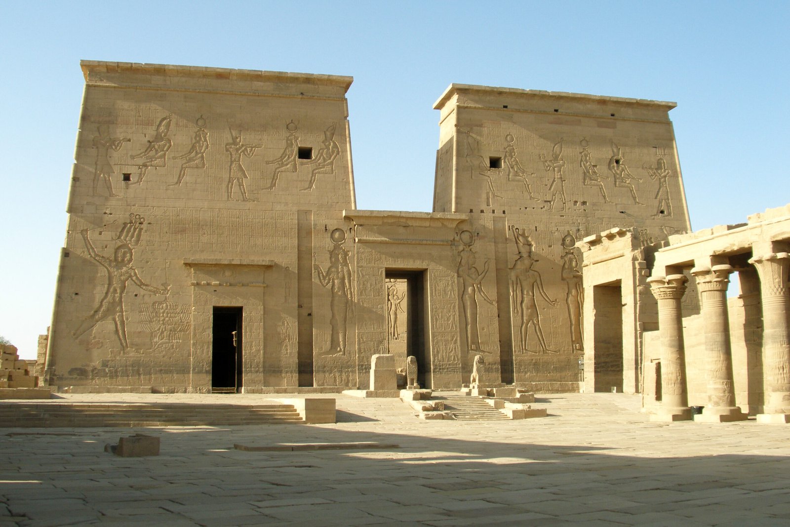 Il cortile del tempio di File ad Assuan con i due piloni e il colonnato nella luce dorata
