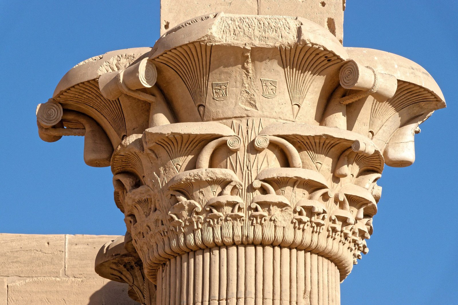 Capitello floreale del chiosco di Traiano a File, scolpito nell'arenaria, contro il cielo azzurro