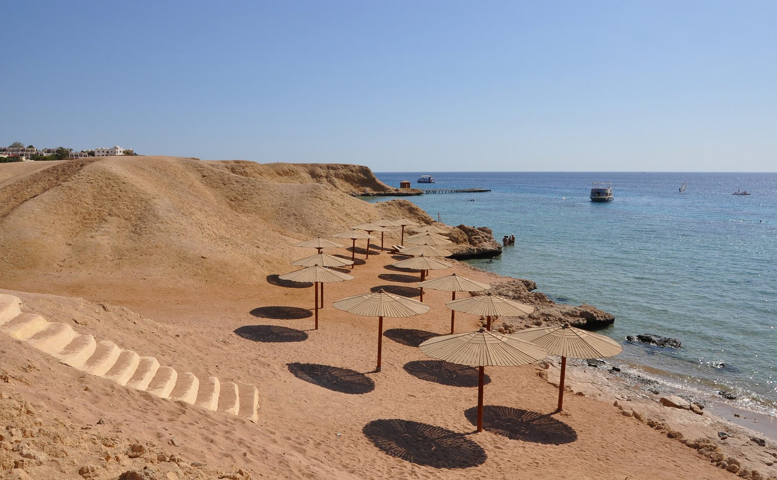 Spiaggia della baia di Naama a Sharm el Sheikh con ombrelloni di paglia e acqua turchese