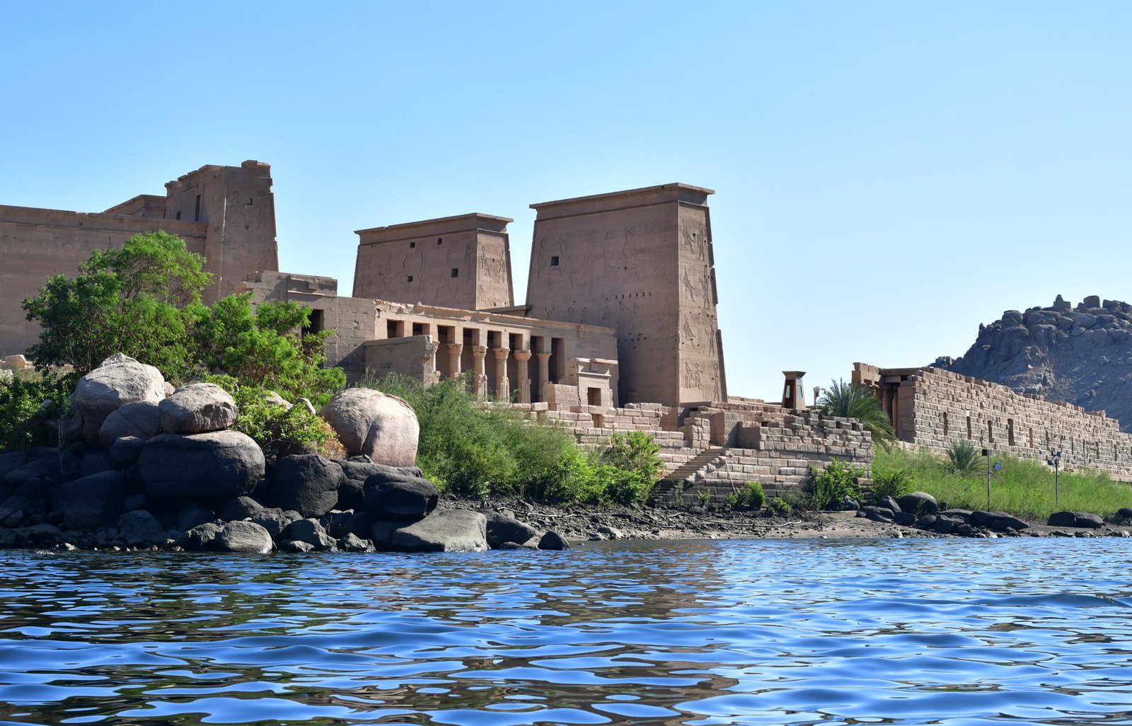 L'isola di Philae vista dall'acqua, con il primo pilone del tempio di Iside sopra i massi di granito