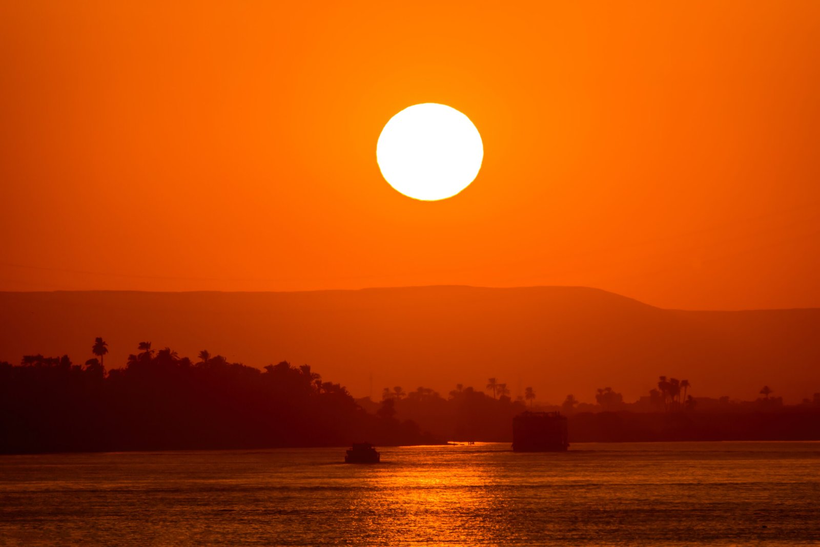 Il Nilo a Luxor al tramonto, con la riva ovest e le palme in controluce