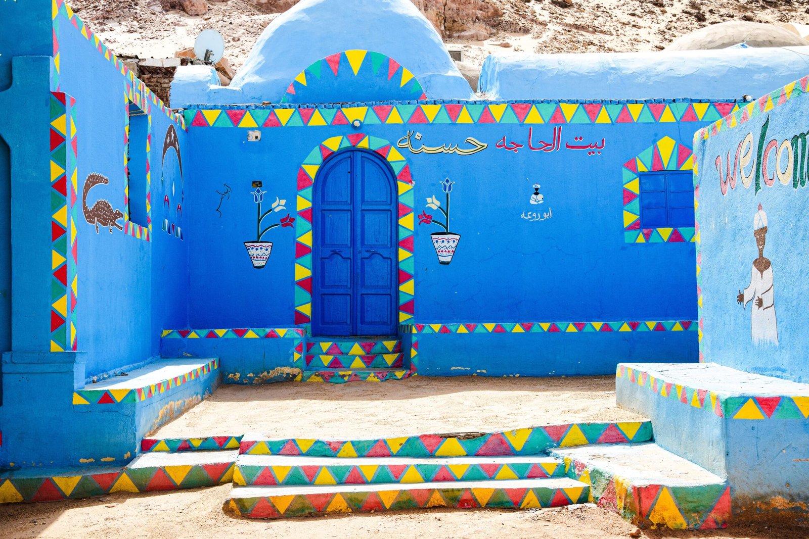 Facciate dipinte di case nubiane con porta azzurra e decori geometrici colorati