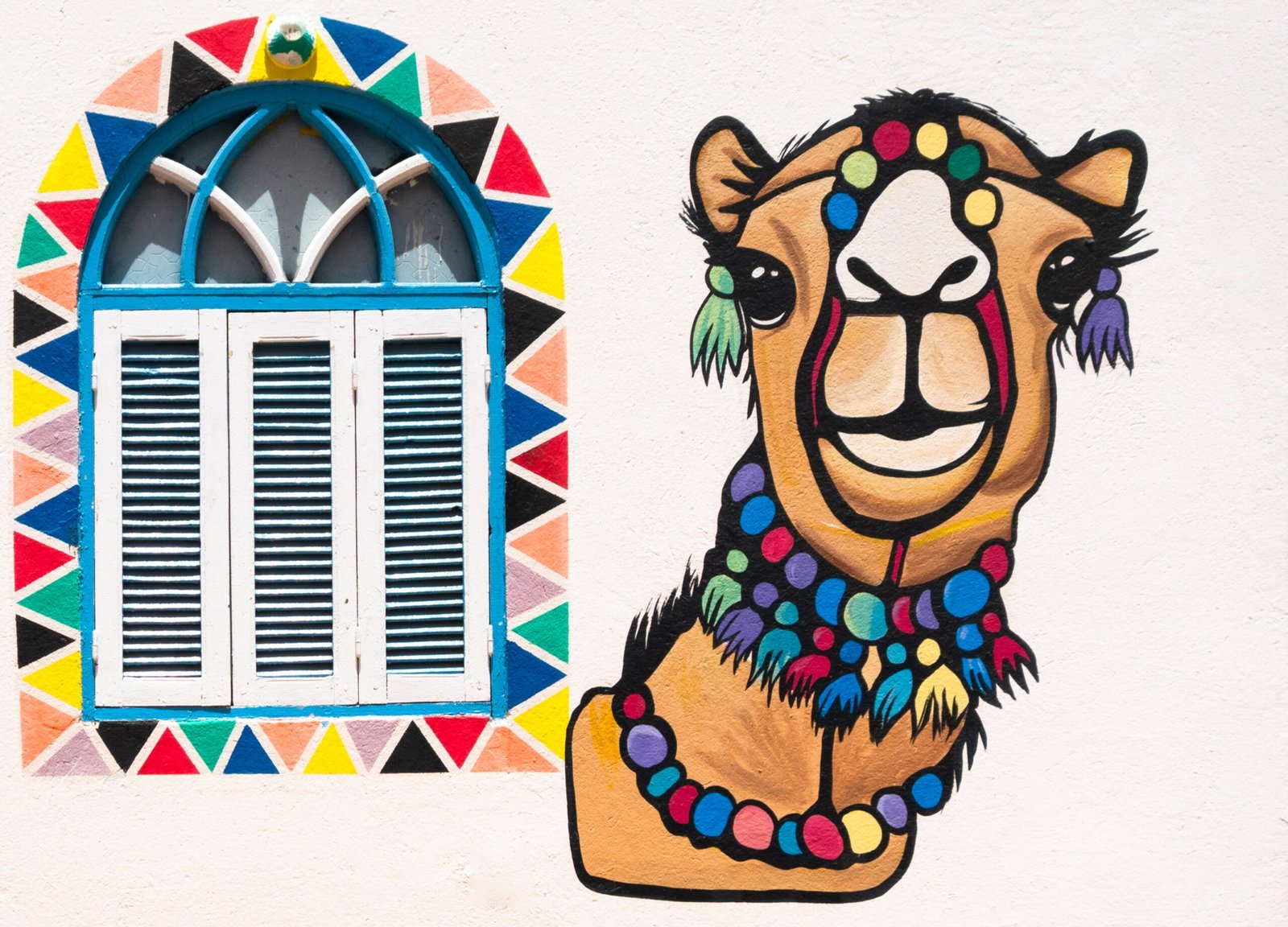 Finestra ad arco con cornice di triangoli colorati e un cammello dipinto sul muro di una casa nubiana a Gharb Soheil, Assuan